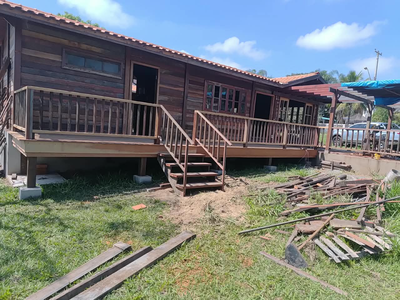 Registros de uma casa de madeira durante a reforma da varanda, com detalhes do piso, dos guarda-corpos e da escada de acesso.