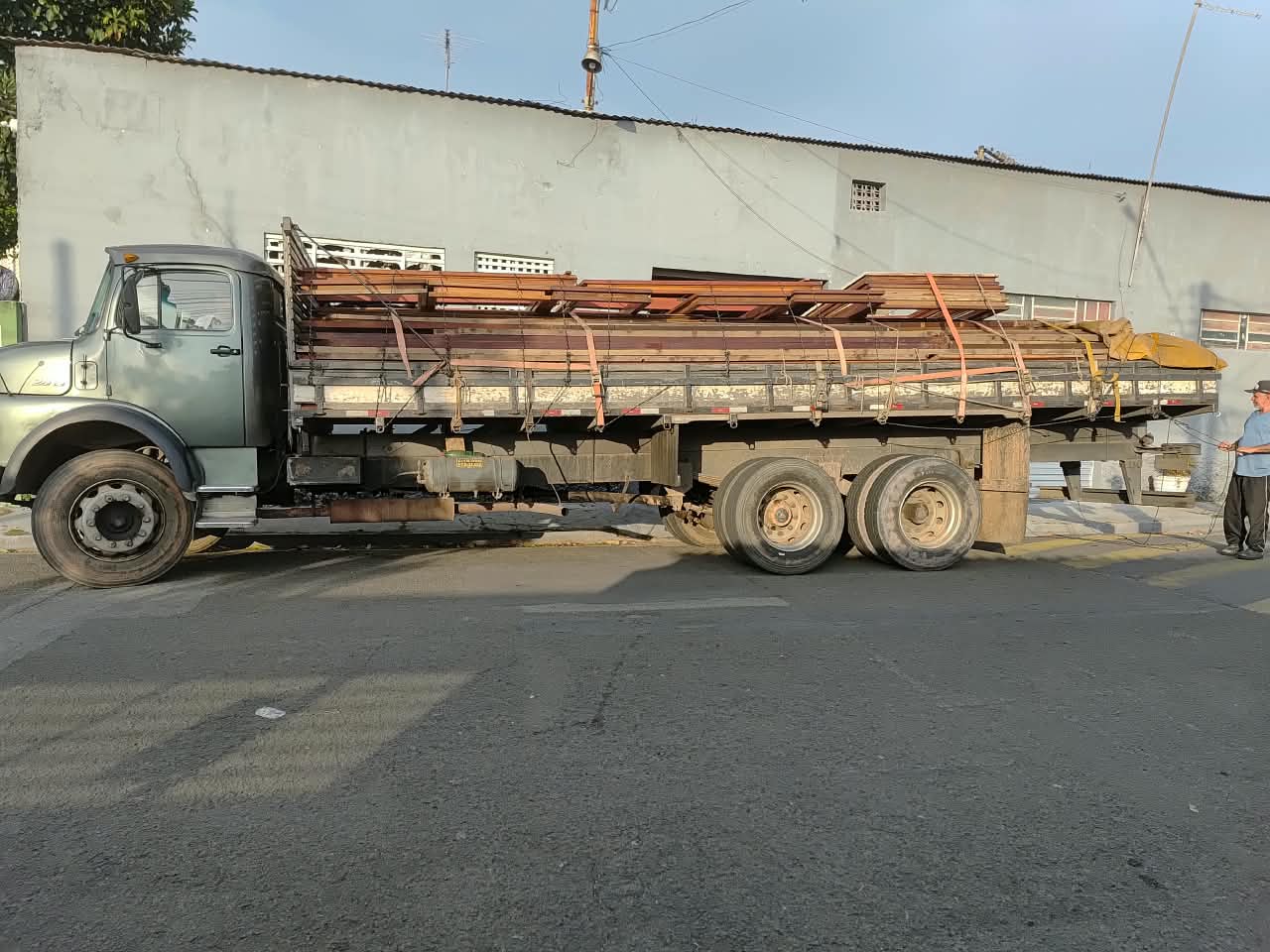 Projeto completo de casa de madeira maciça: da chegada das peças no caminhão até a montagem final, com varanda, telhado e esquadrias concluídos.